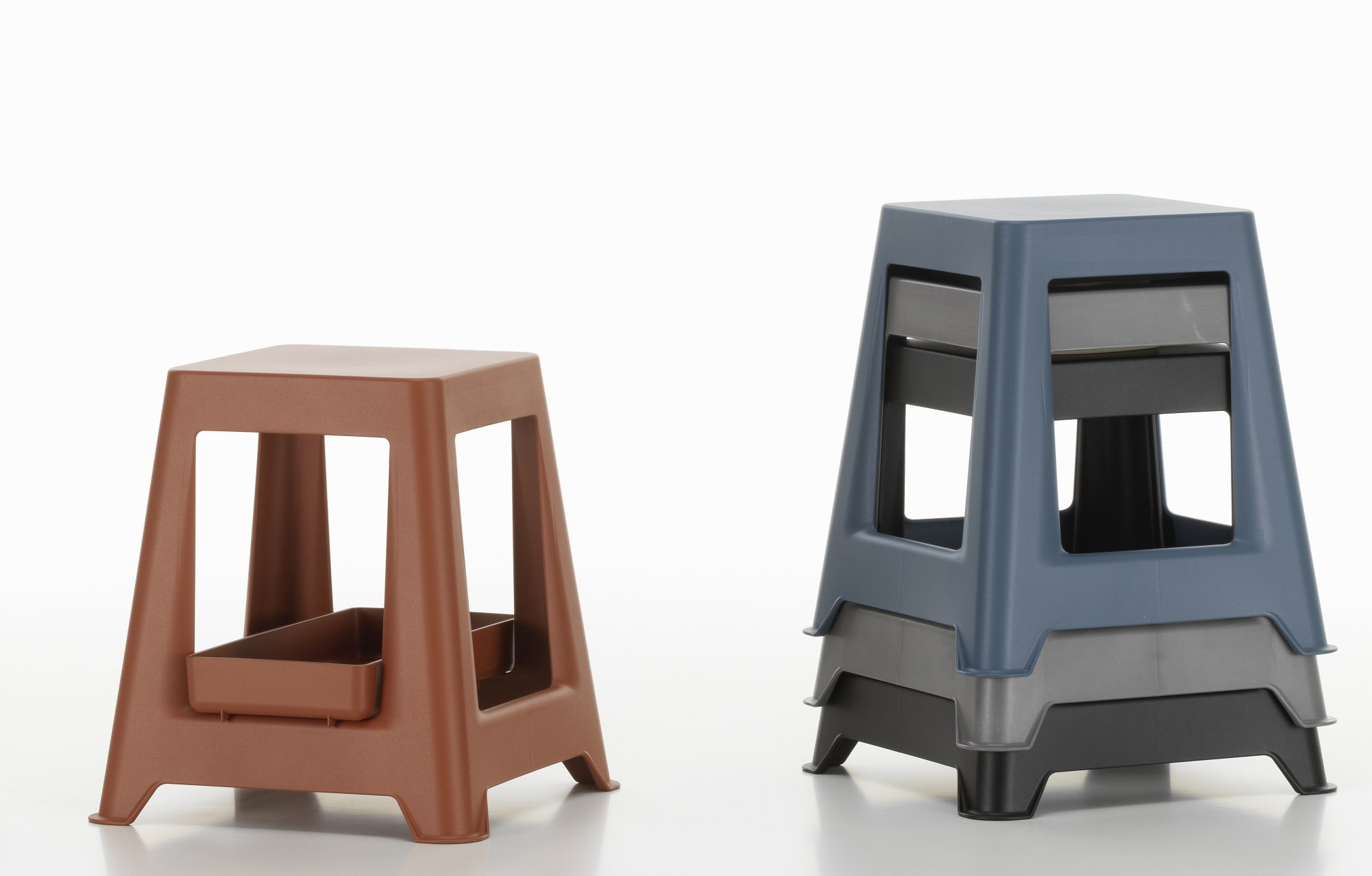 Chap Hocker von Vitra in Braun und gestapelt in Blau, Grau und Schwarz.