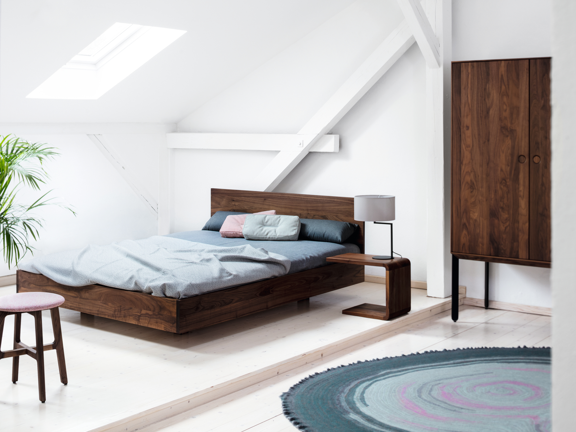 Simple HI 79 Holzbett aus Nussbaum mit Nachttisch und Kleiderschrank in hellem Schlafzimmer.