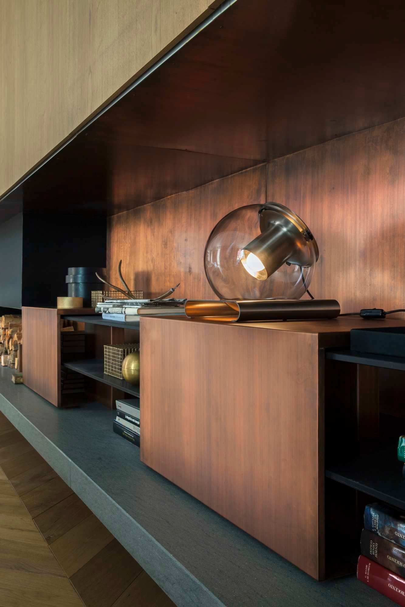 The Globe Tischleuchte 228 von Oluce auf einem Regal mit Kupferverkleidung, modernes Design.