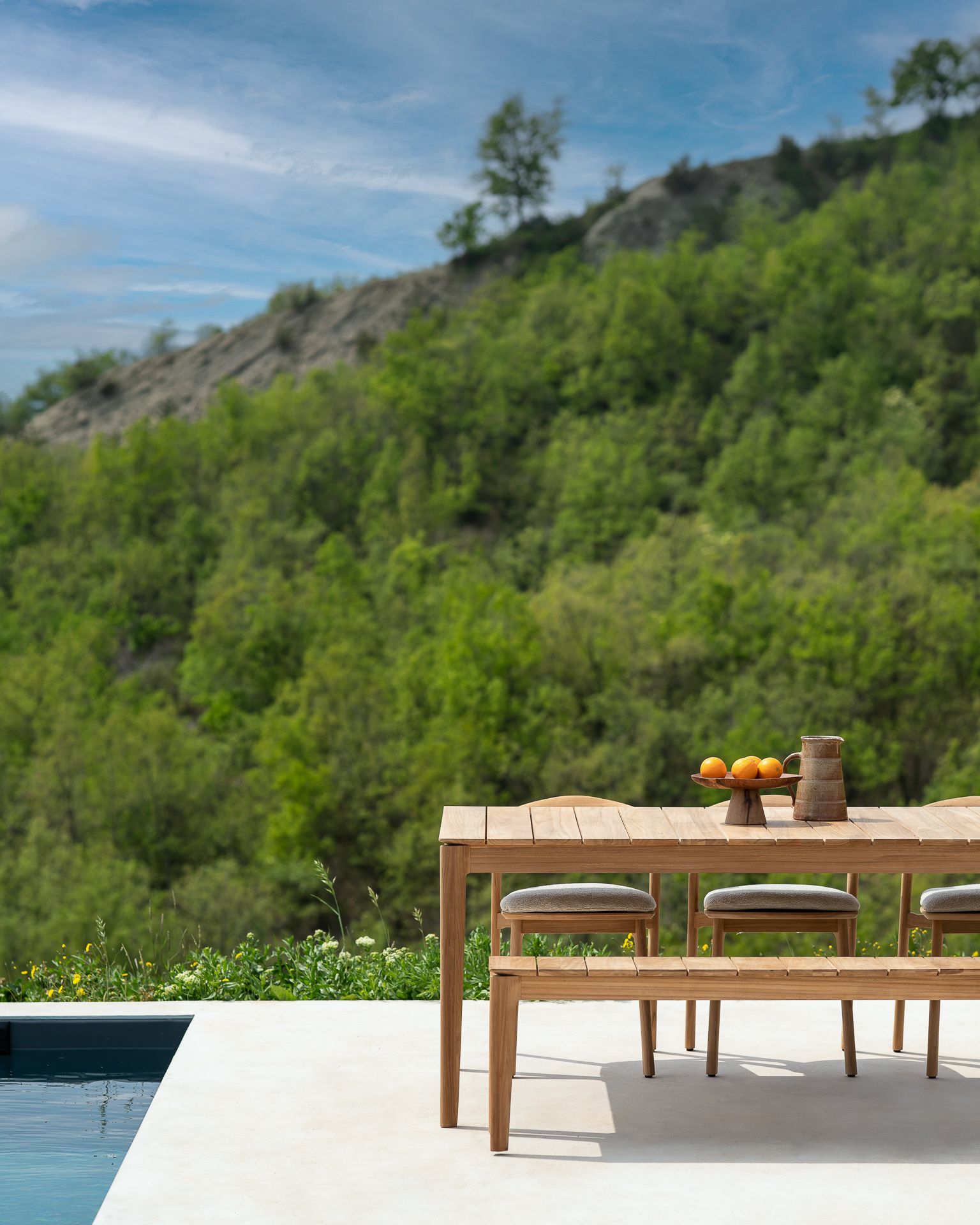Bok Outdoor Bank aus Teakholz, 3-Sitzer, vor grüner Landschaft. Gartenmöbel für Terrasse.