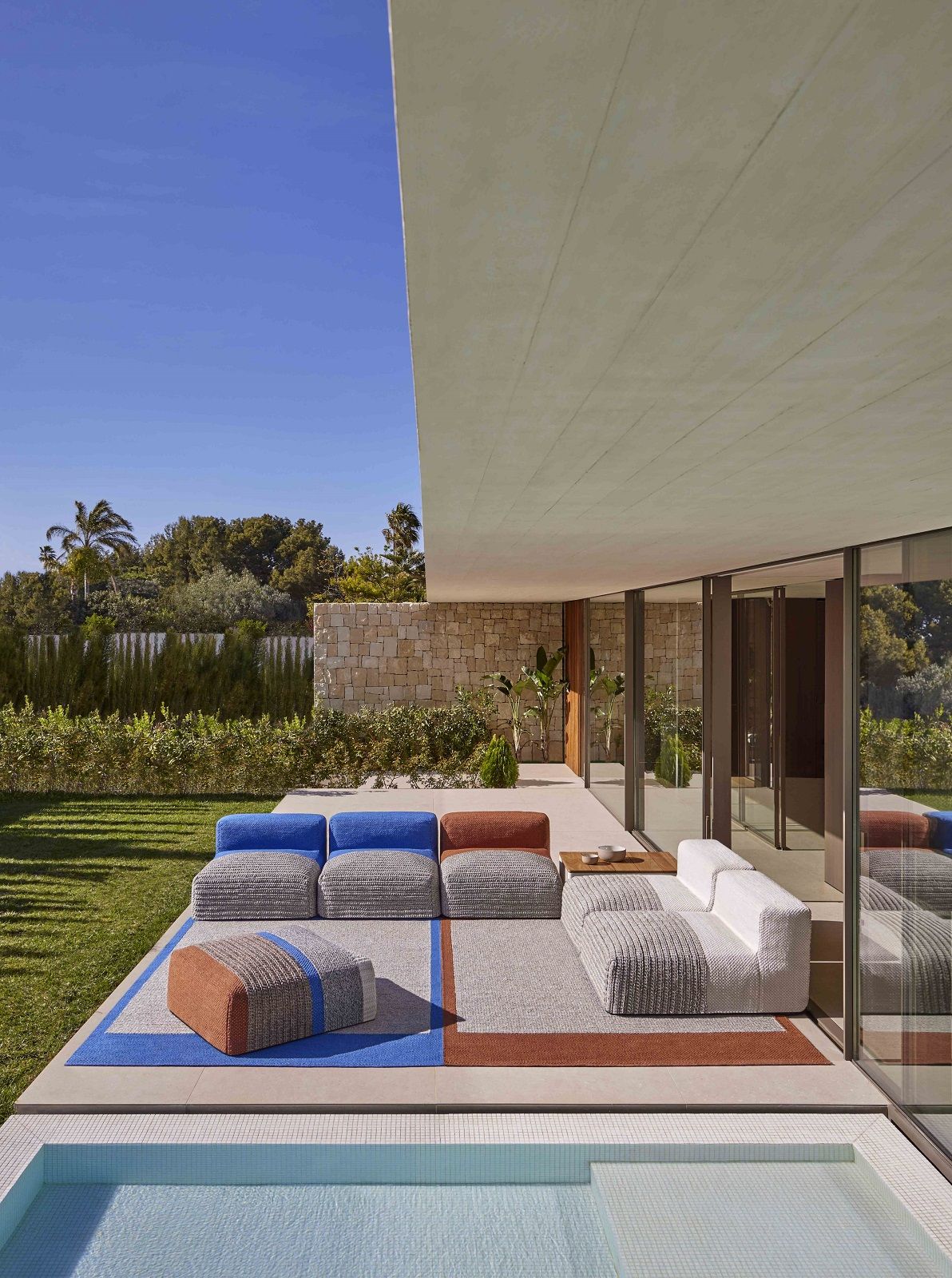 Mangas Outdoor Rug Teppich: Moderner Outdoor-Teppich mit modularen Sitzmöbeln in Blau, Braun und Weiß.