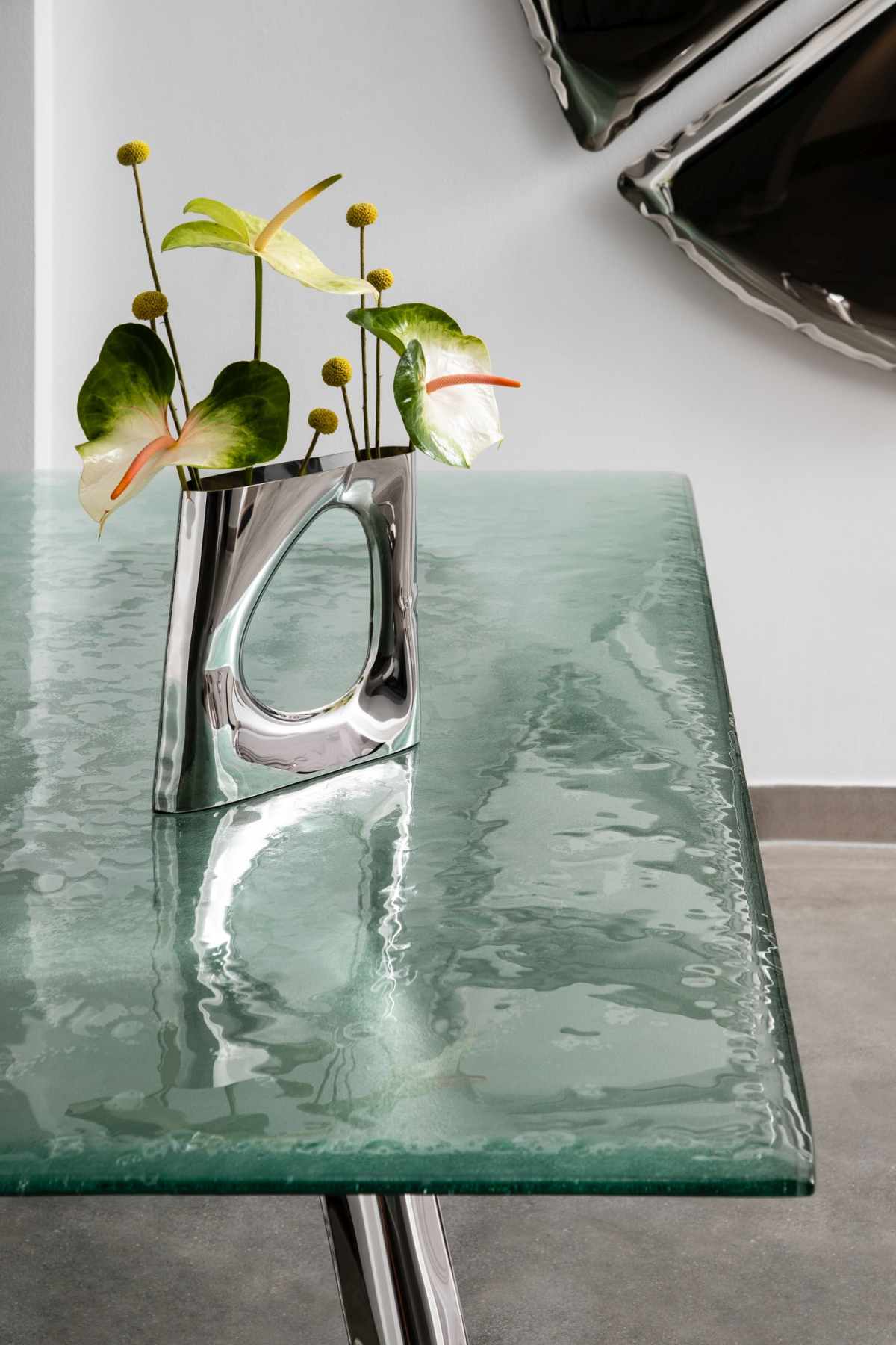 Detailaufnahme des Nogi Tischgestells von Zieta mit grüner Tischplatte und silbernen Beinen.