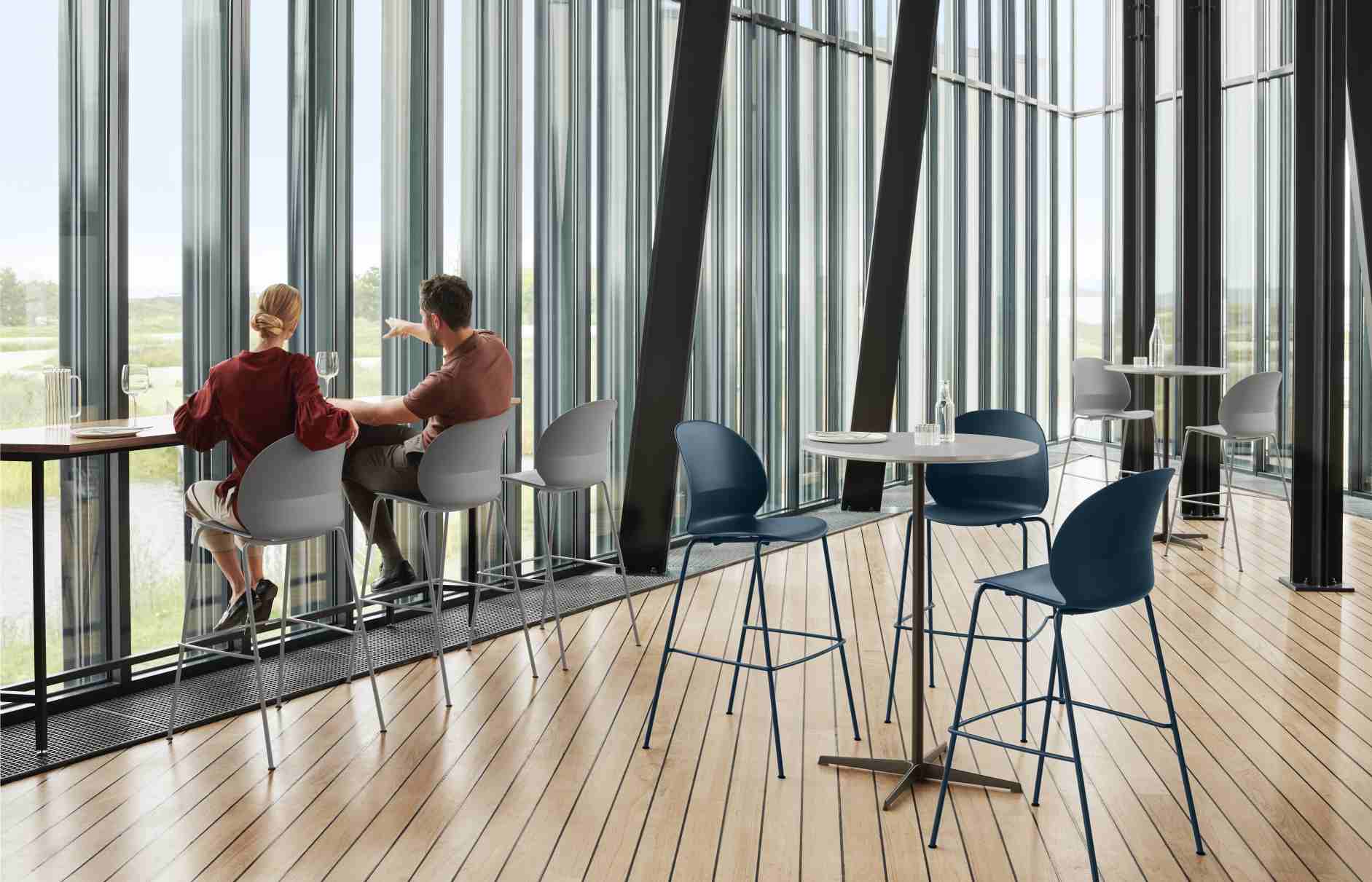 Zirkular Stehtisch von Fritz Hansen mit Personen an Stehtischen und Barhockern in modernem, lichtdurchflutetem Raum.