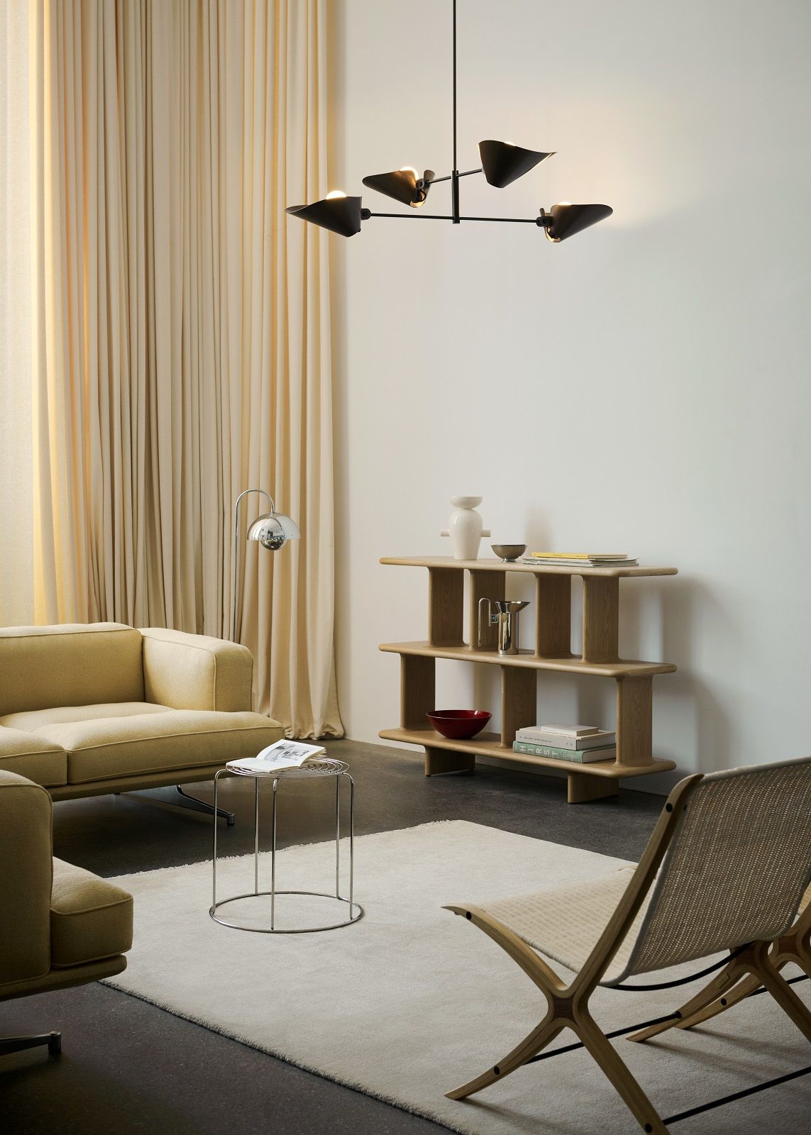 AndTradition Bonnet Pendelleuchte SC91-93 in schwarzem Design über modernem Wohnzimmer mit Möbeln.