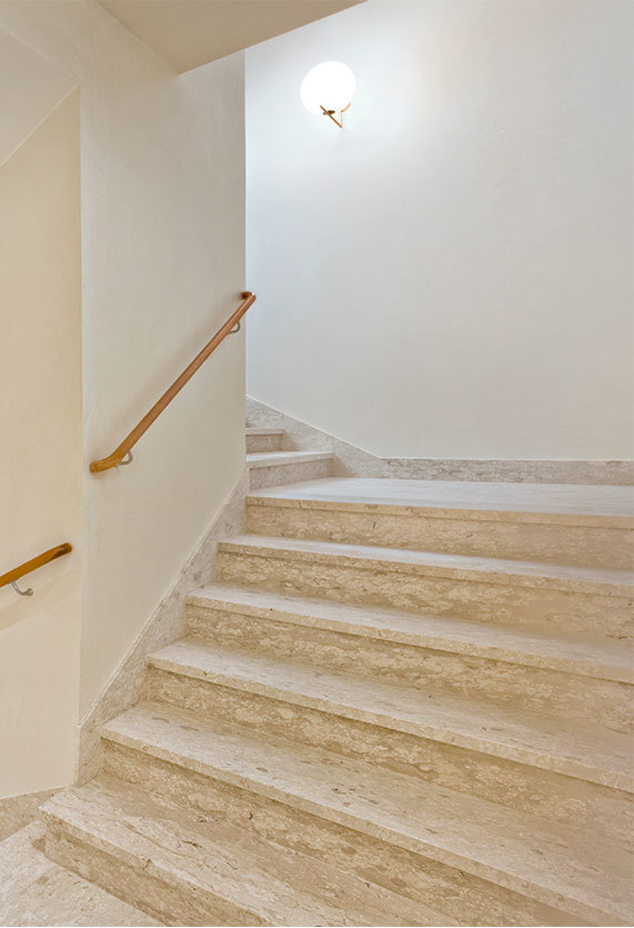 Treppenaufgang mit Flos IC Lights Wandleuchte, die eine sanfte, indirekte Beleuchtung spendet.