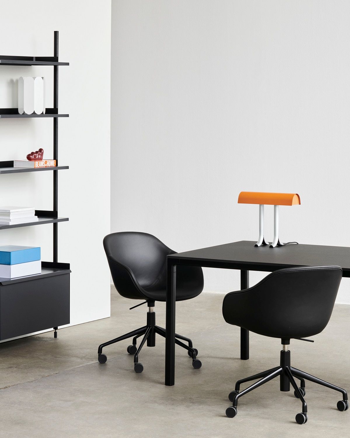 Zwei schwarze About a Chair AAC253 Bürostühle von Hay an einem schwarzen Tisch.