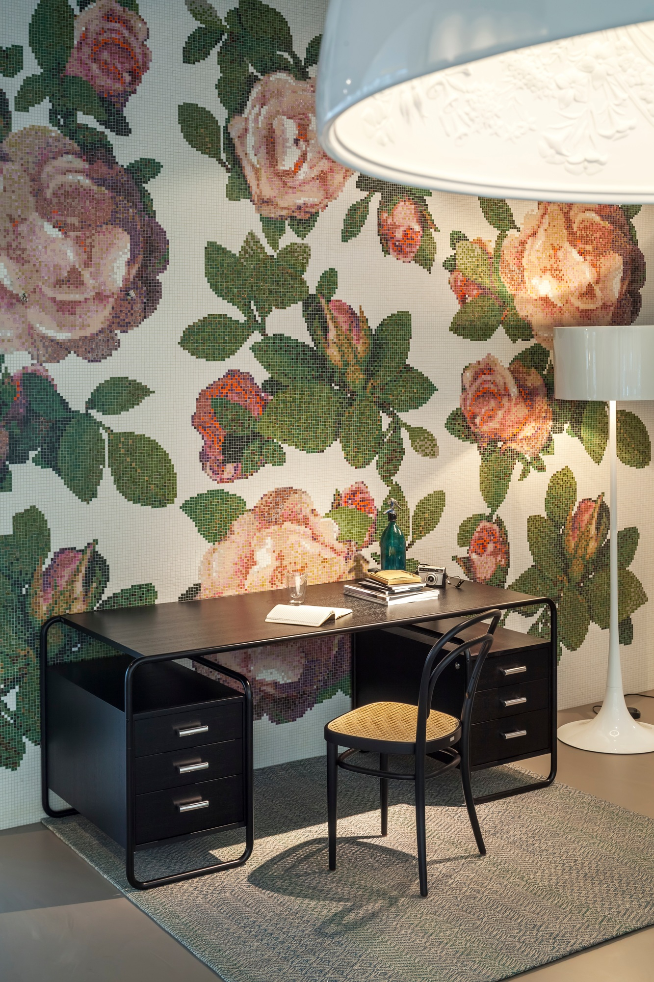 Schwarzer S 285 Stahlrohr Schreibtisch von Thonet mit Schubladen und passendem Stuhl vor floraler Wand.