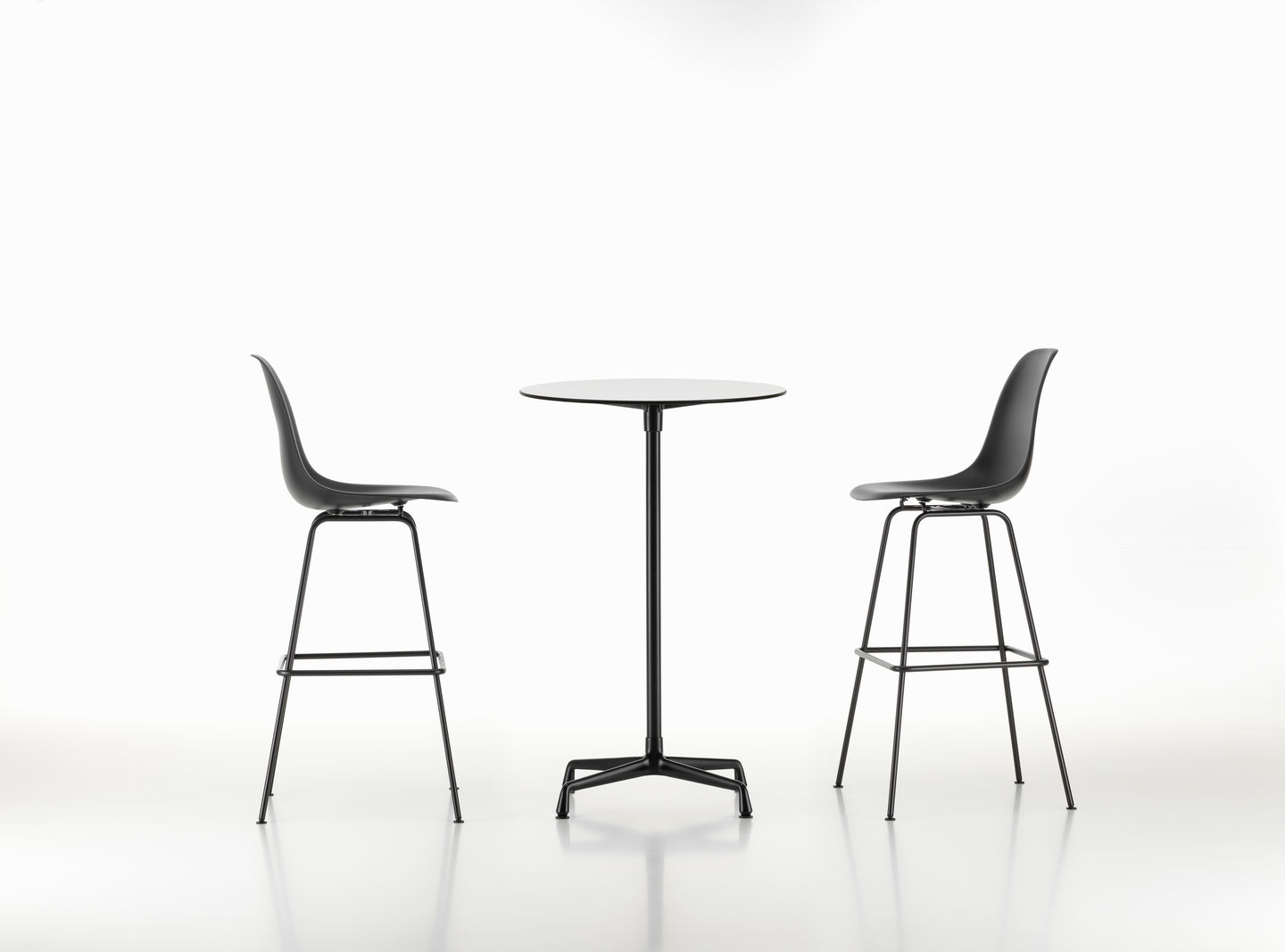 Zwei schwarze Eames Plastic Bar Stools von Vitra mit einem runden Tisch auf weißem Hintergrund.