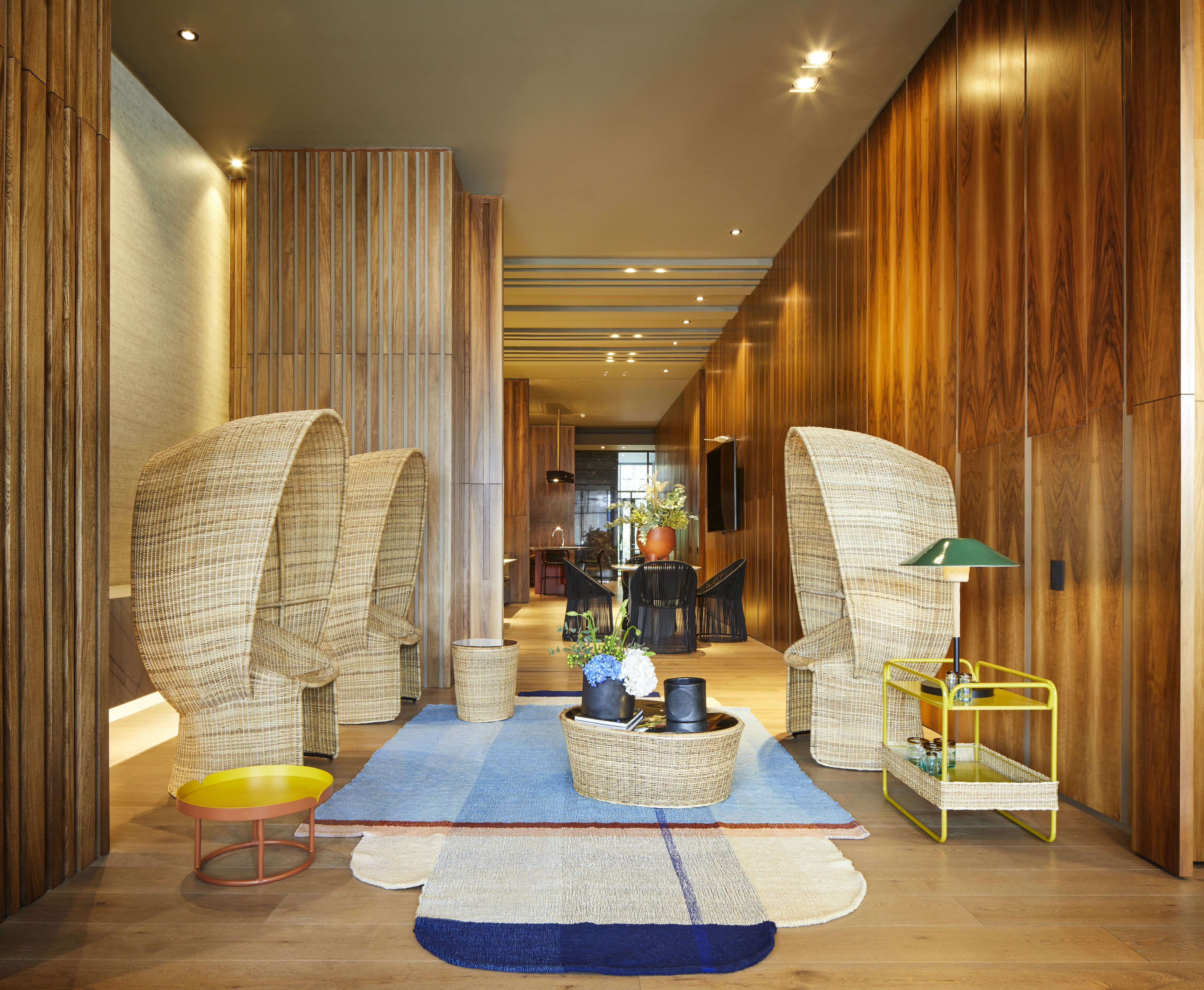 Cartagenas Ames Sessel aus Naturrohr im modernen Wohnzimmer mit Teppich und Beistelltischen.