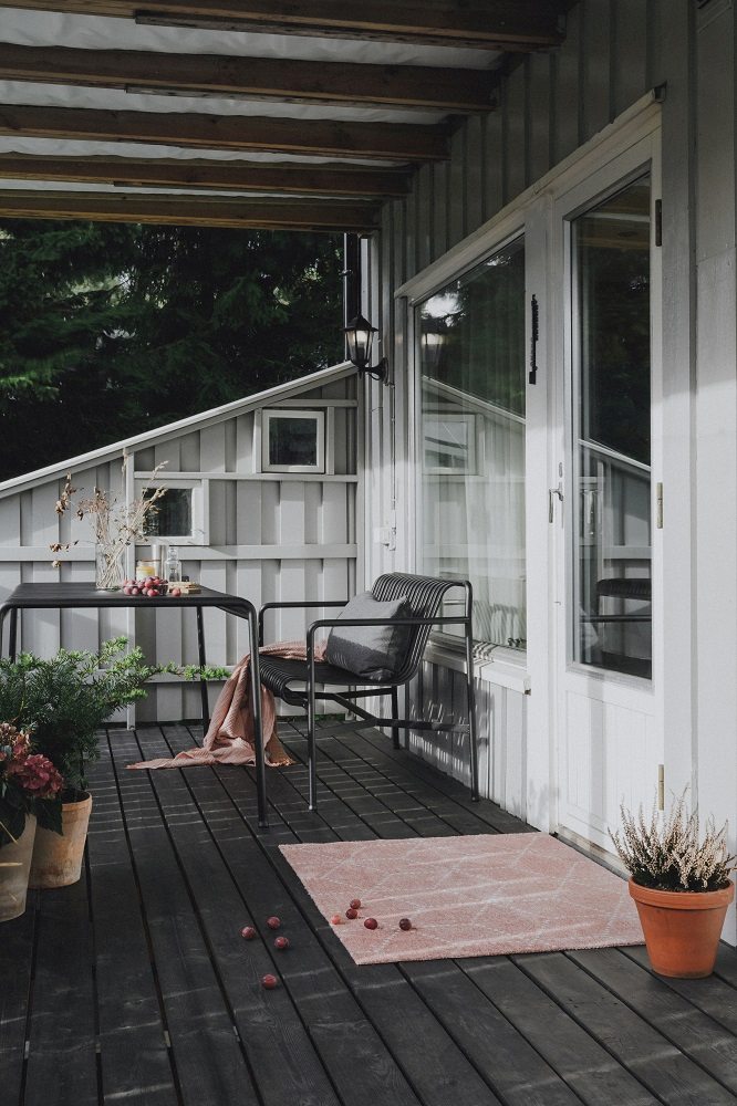 Helle Hagl Fußmatte auf dunkler Holzterrasse, ideal für drinnen und draußen. Heymat Fußabtreter.