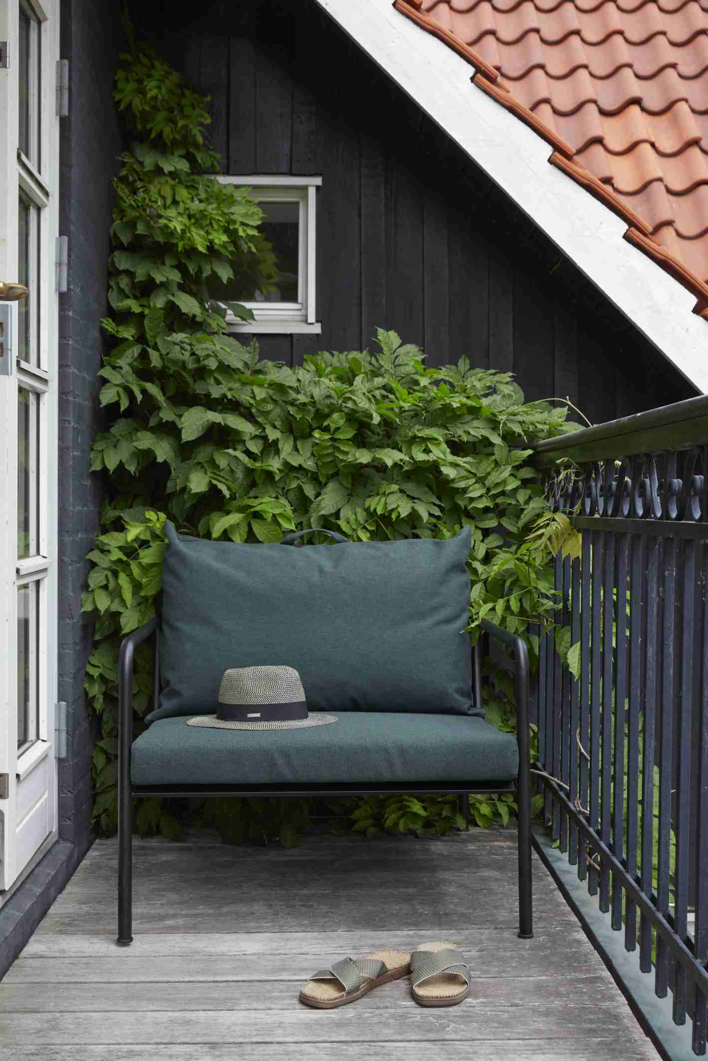 Avon Lounge Chair: Grüner Outdoor Sessel von Houe mit Kissen, Hut und Sandalen.