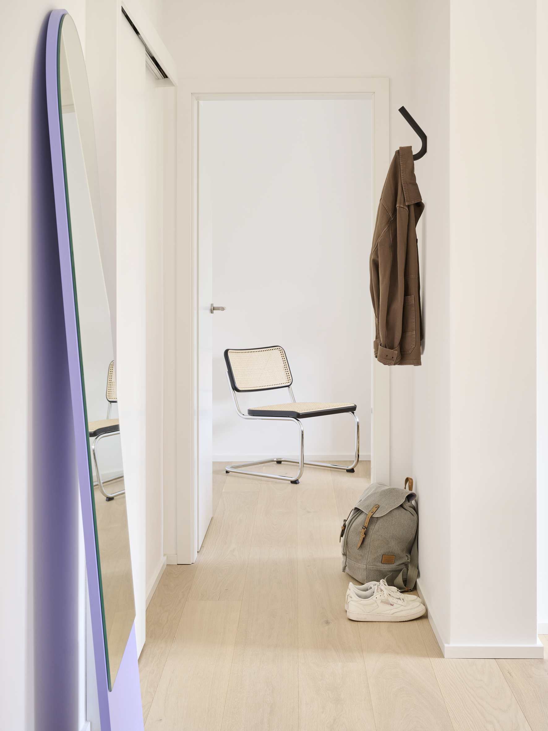 Flur mit Thonet S 12 Wandhaken, Jacke, Rucksack und Schuhen. Minimalistisches Design für Garderobe und Aufbewahrung.