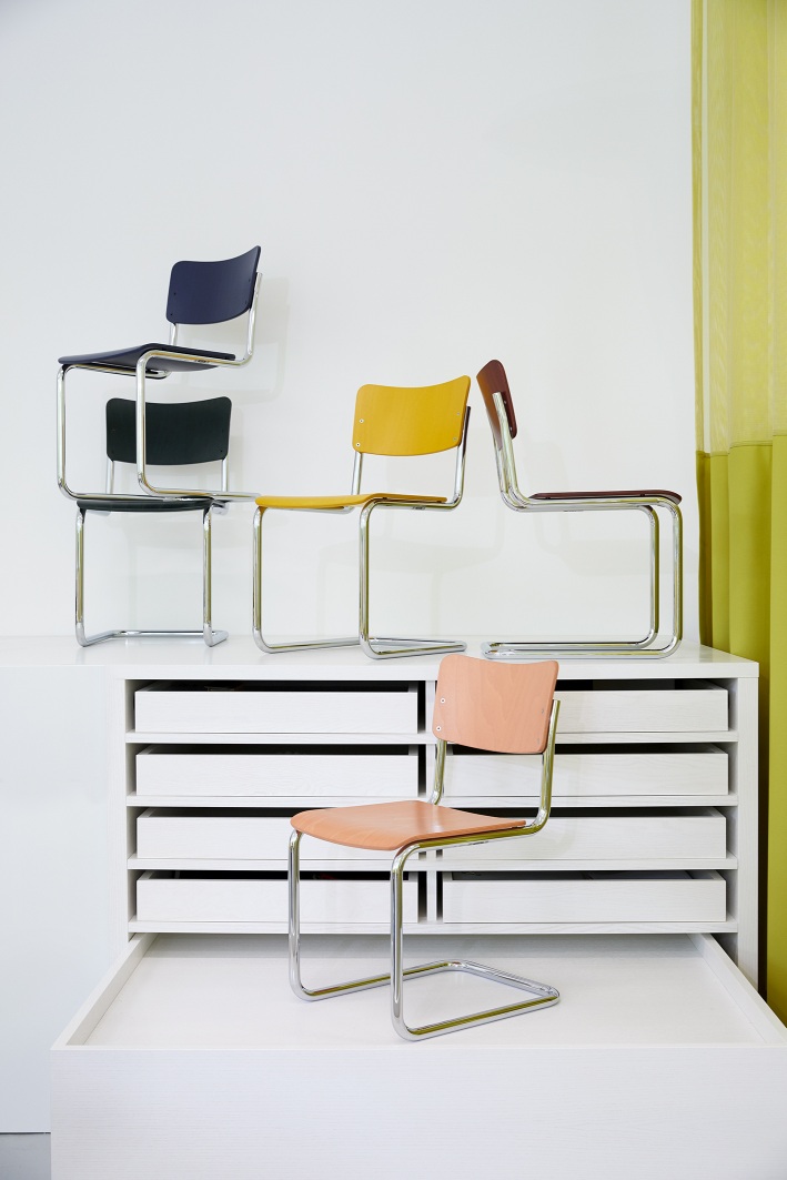 Mehrere Thonet S 43 K Kinderstühle Freischwinger in verschiedenen Farben gestapelt auf weißem Schrank.