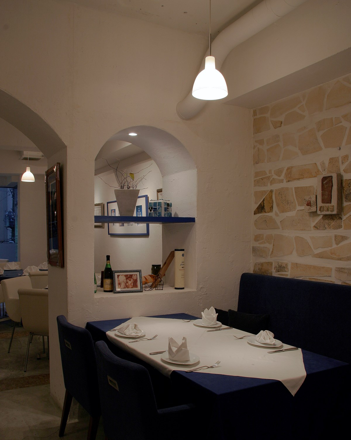 Innenaufnahme eines Restaurants mit einer Toldbod Pendelleuchte von Louis Poulsen über einem gedeckten Tisch.