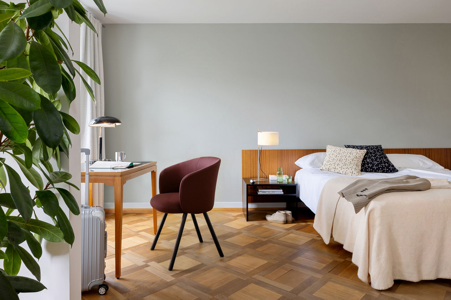 Nahaufnahme eines burgunderroten Mikado Armlehnstuhls von Vitra in einem modern eingerichteten Schlafzimmer.