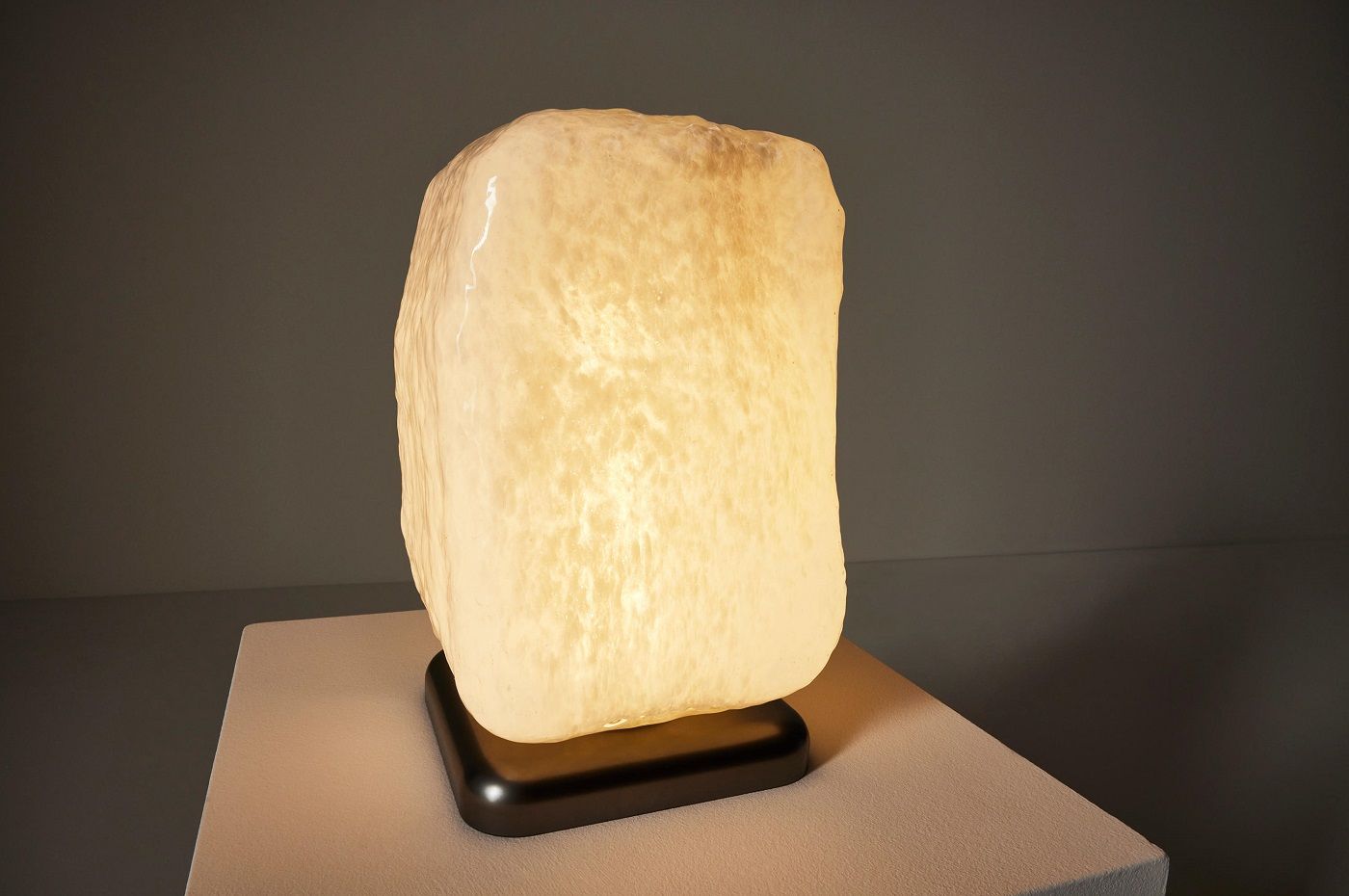 Wax Stone Tischleuchte von Cassina: Nahaufnahme der modernen Leuchte mit warmem Licht und schwarzem Sockel.