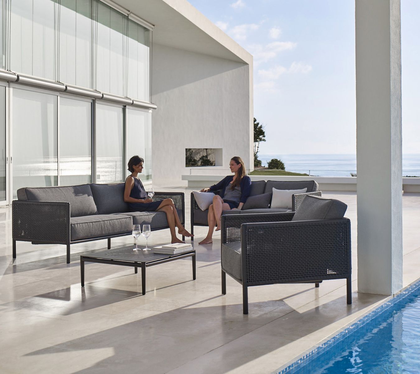 Encore Sofa: Graues 2-Sitzer Gartensofa mit AirTouch Kissen und passendem Sessel auf einer Terrasse.