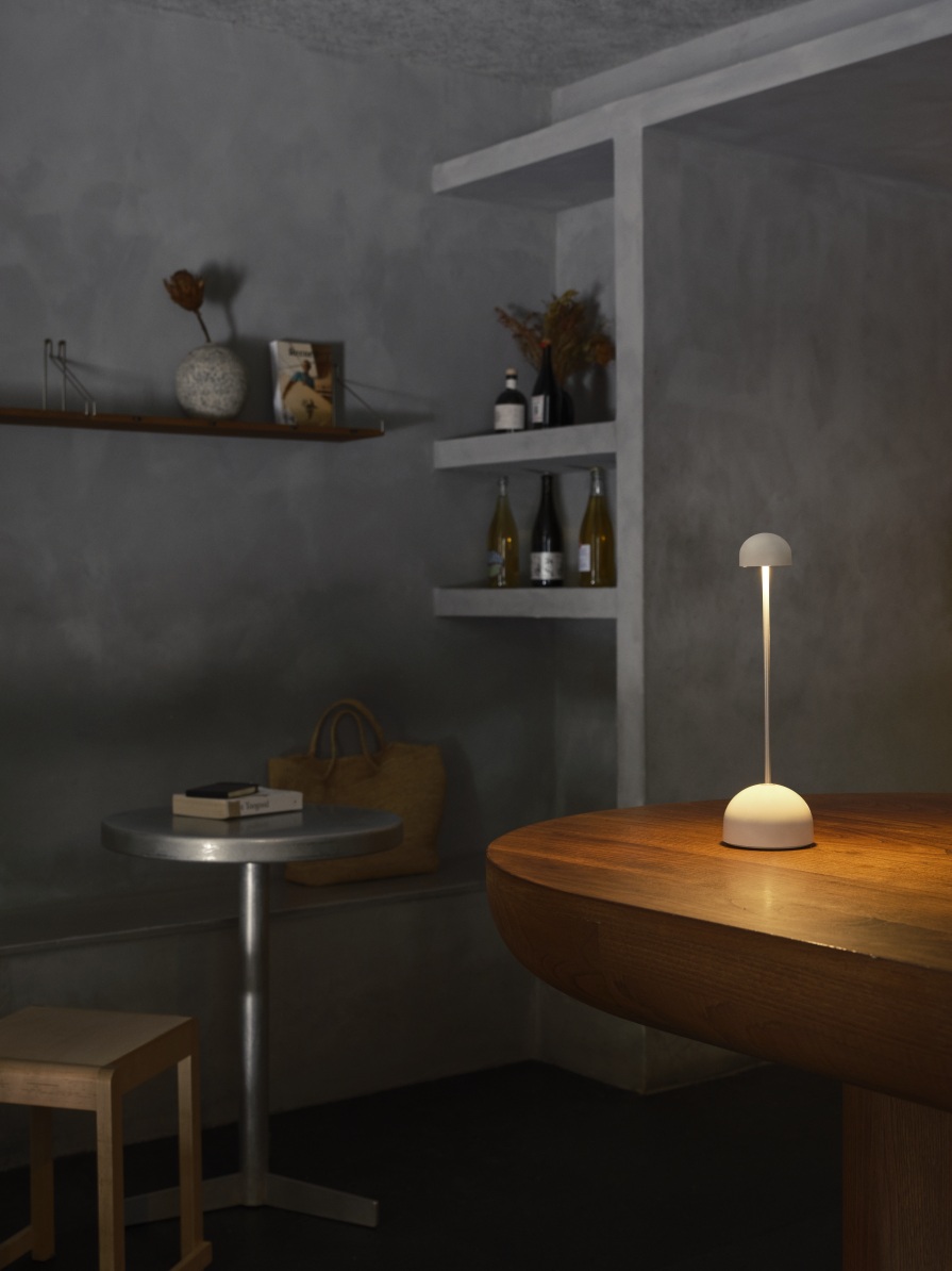 Sips Akkuleuchte von Marset in Weiß/Silber auf Holztisch, stimmungsvolle Tischleuchte für Innenräume.