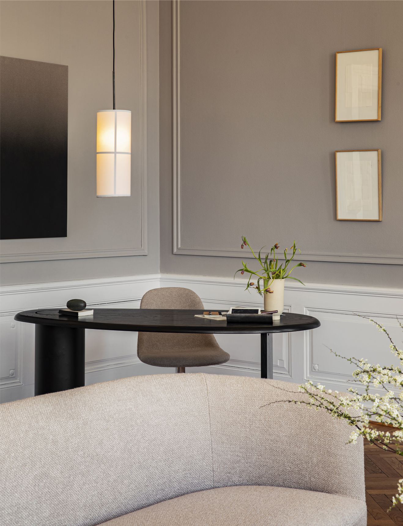 Nahaufnahme des Audo Tearoom Sofas in Arktis Beige, kombiniert mit Schreibtisch, Stuhl und Pendelleuchte in einem eleganten Interieur.