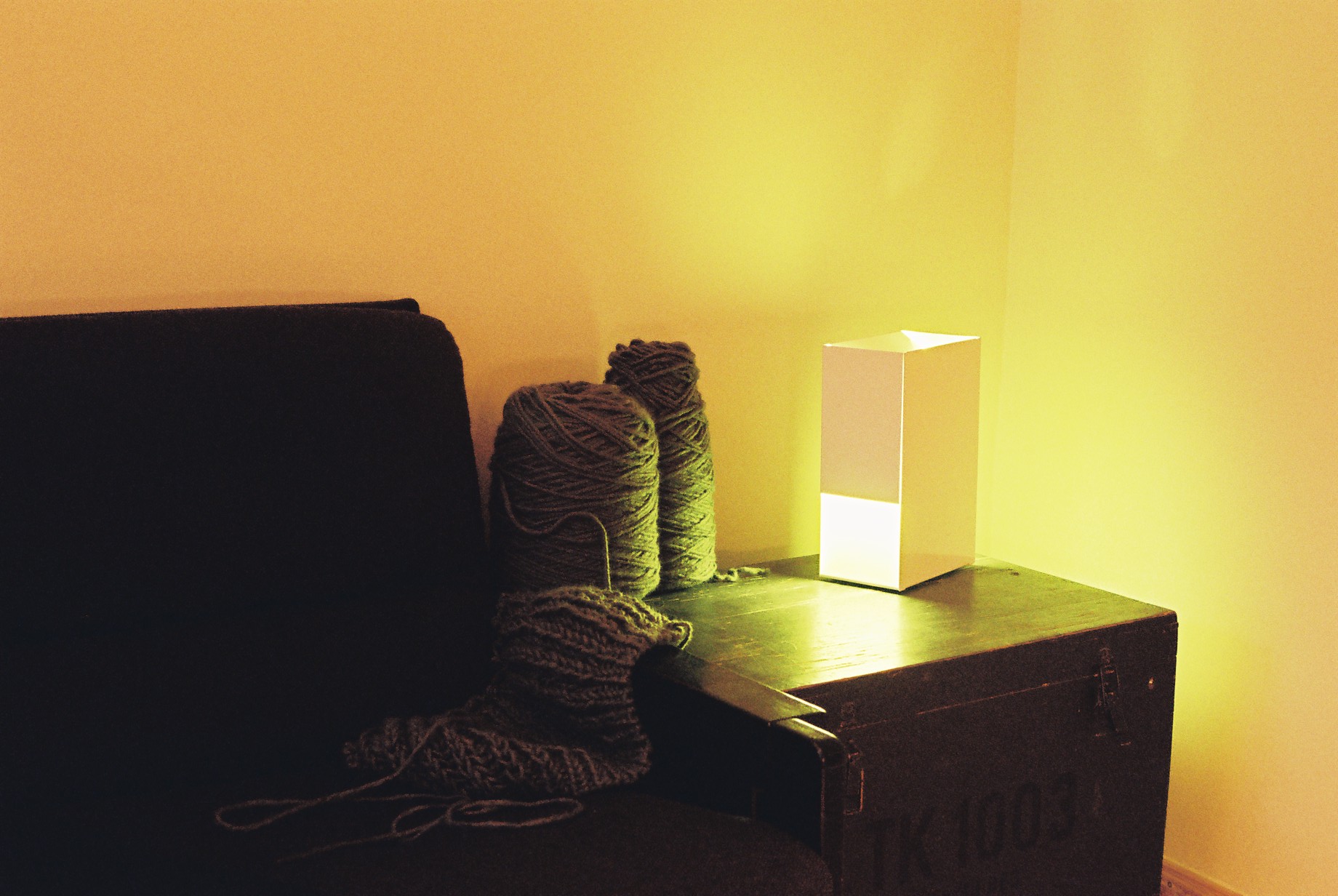 Weiße Linea1 Tischleuchte von Müller Möbelwerkstätten neben Wolle auf einem Nachttisch.