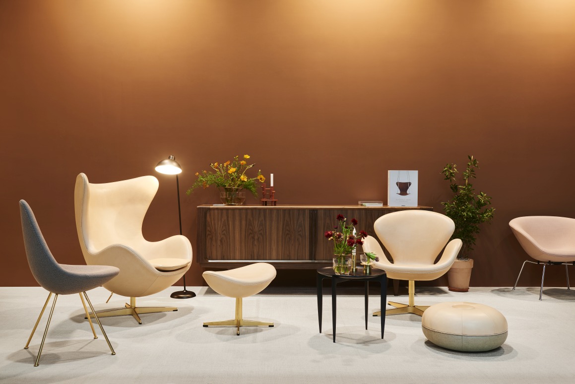 Wohnzimmer-Szene mit Fritz Hansen Pouf Large Hocker in Warm Sand und weiteren Designermöbeln.