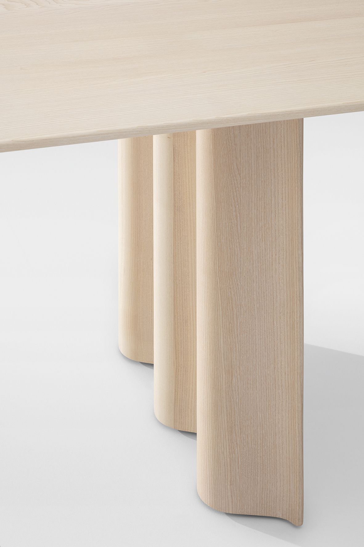 Detailaufnahme des Curtain Tisches: Rechteckiger Esstisch mit hellen, gerundeten Holzbeinen.