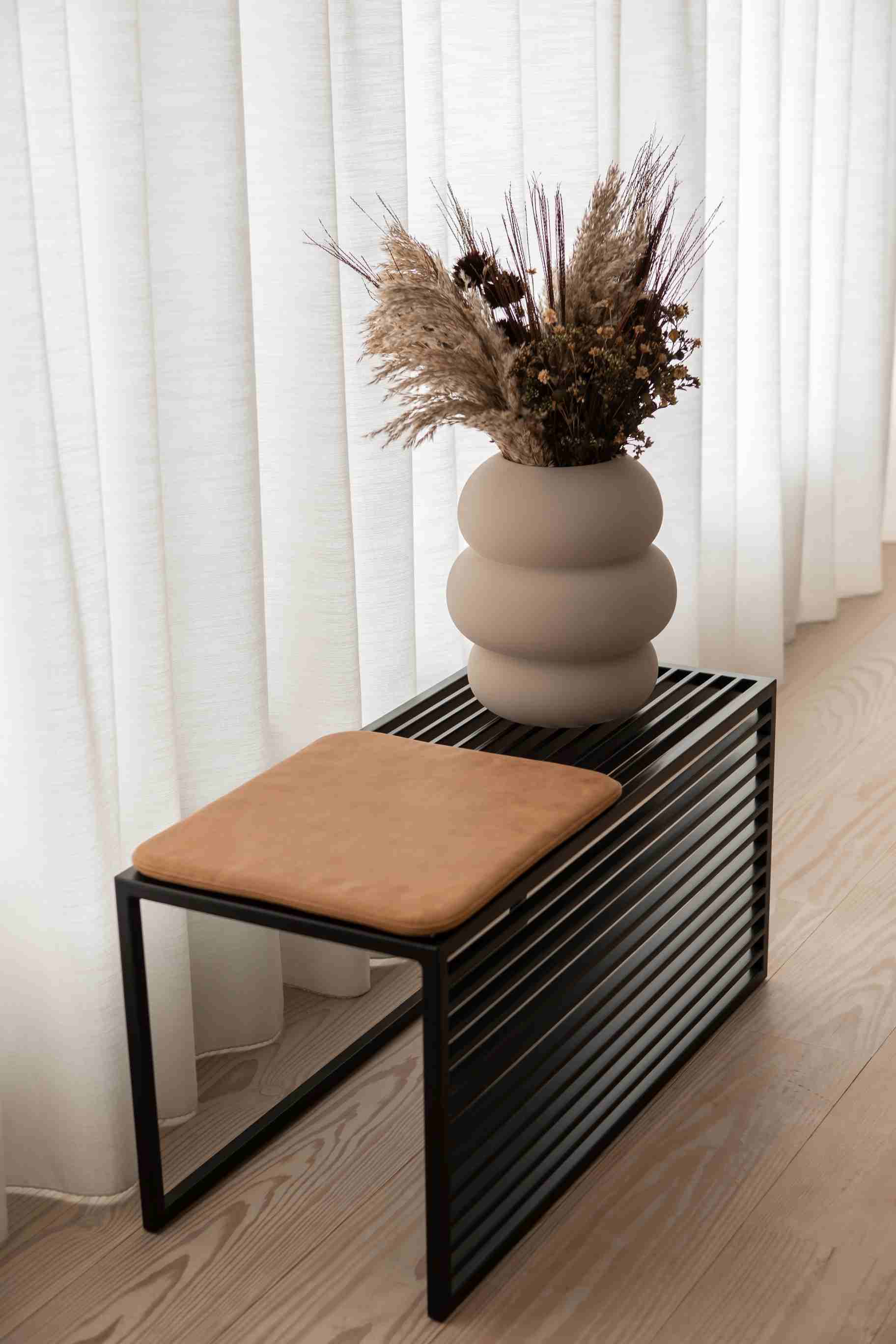 Element Bench Bank novoform mit braunem Sitzkissen und dekorativer Vase im minimalistischen Interieur.