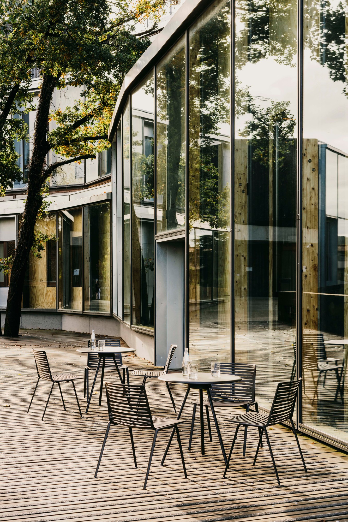Zebra Outdoor Stühle Fast aus Metall mit Tisch auf einer Terrasse vor einem modernen Gebäude.
