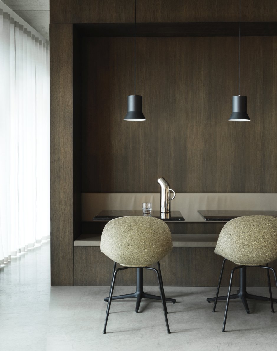 Zwei Mat Chair Steel Stühle von Normann Copenhagen vor dunkler Holzwand und Tisch.