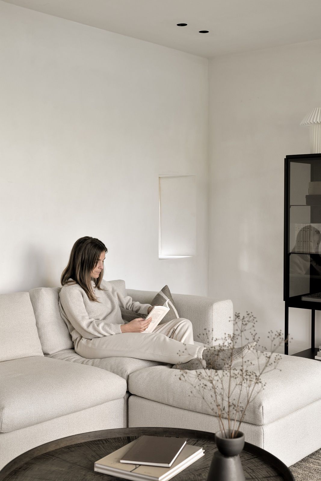 Frau liest auf Sofa mit Ethnicraft Slice Holztablett als Couchtisch.