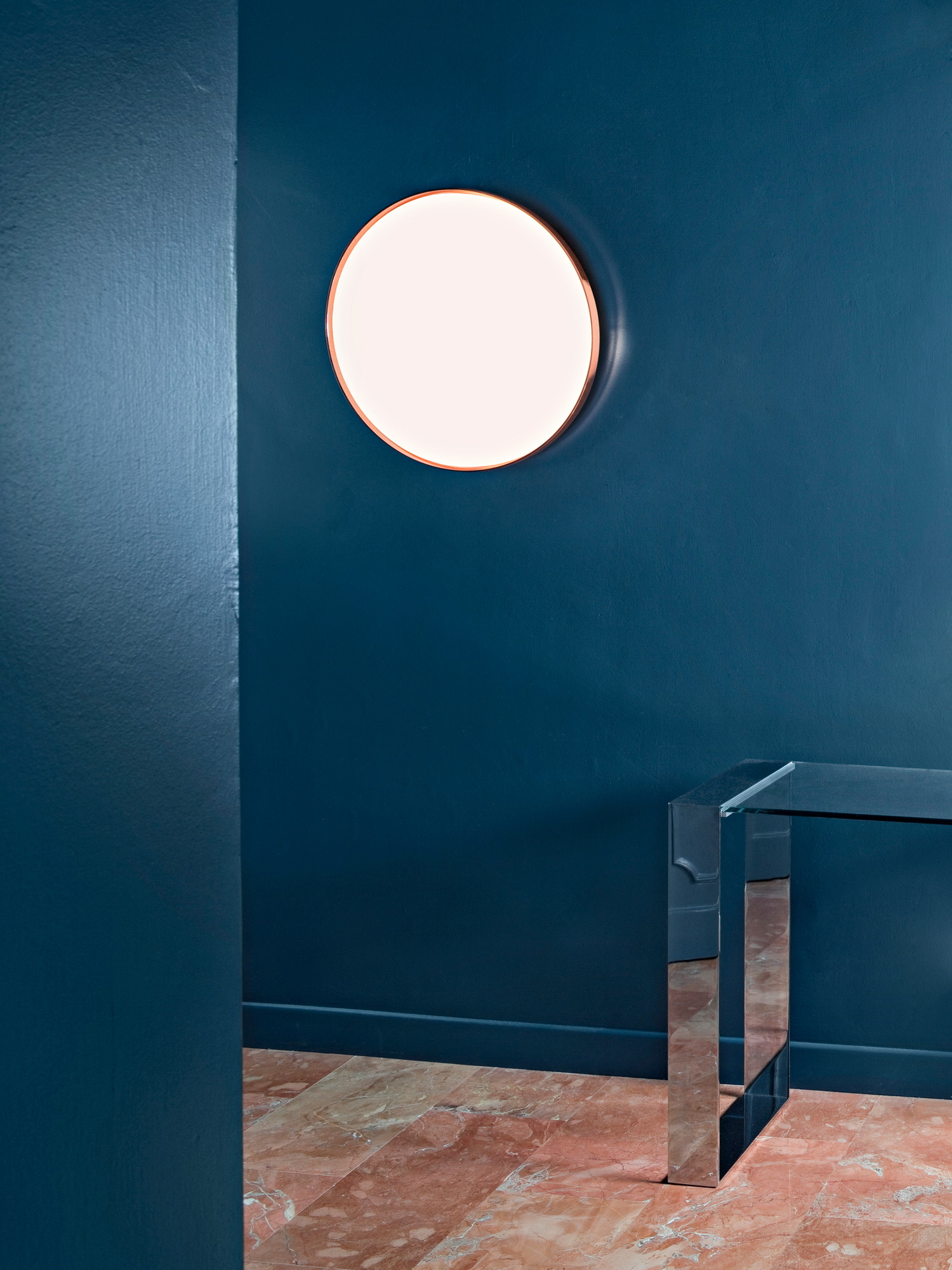 Runde Clara Wandleuchte von Flos an blauer Wand, indirekte Beleuchtung, modernes Design.