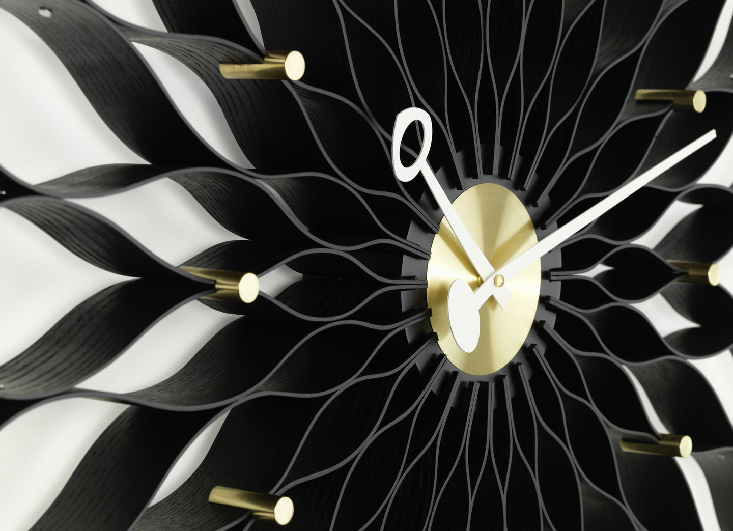 Detailaufnahme der Vitra Sunflower Clock Wanduhr in Esche schwarz mit Messing-Akzenten.