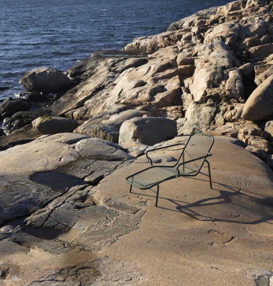 Vig Chaise Longue von Normann Copenhagen, grüne Outdoor Liege auf Felsen am Meer.