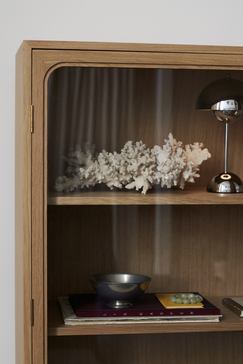 Nahaufnahme des AndTradition Trace SC88 Schranks aus Eiche mit Glasvitrine und Deko-Objekten.