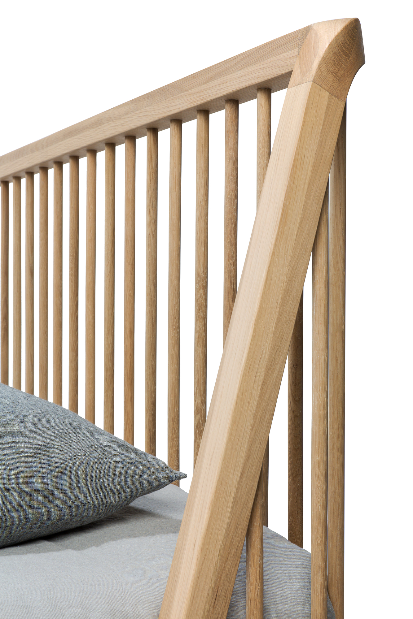 Detailaufnahme: Ethnicraft Spindle Bett aus Eiche mit Lattenrost und grauem Kissen. Massivholzbett für Schlafzimmer.
