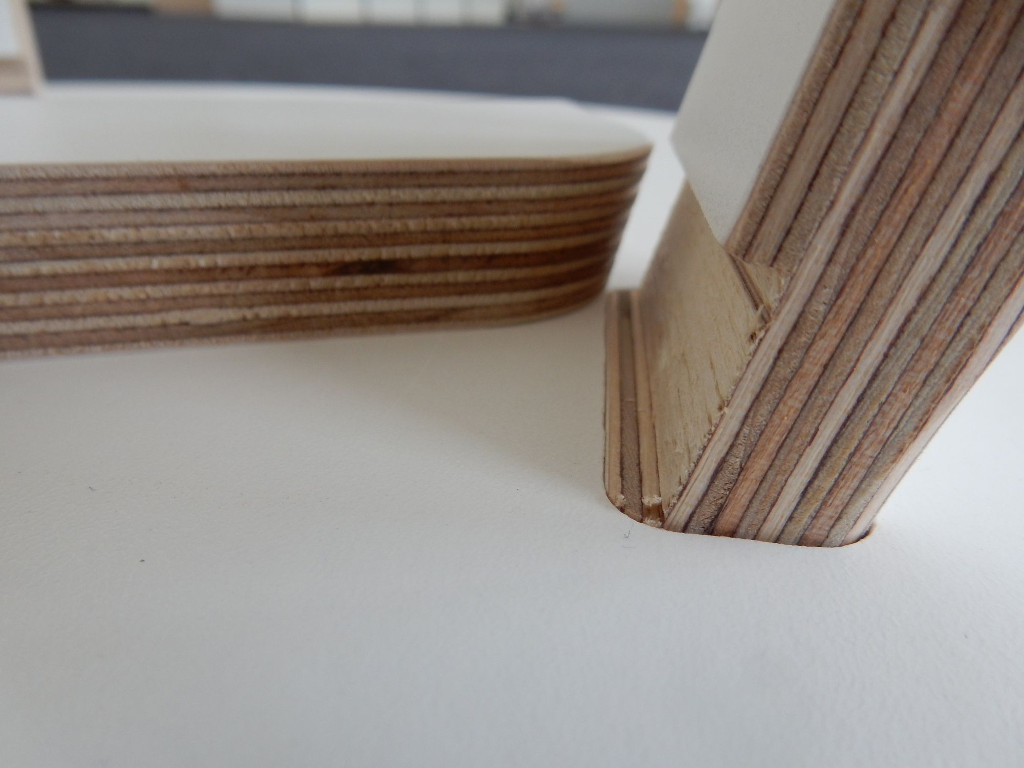 Detailaufnahme vom Tojo Rund Tisch: Tischbein und Tischplatte aus Schichtholz.