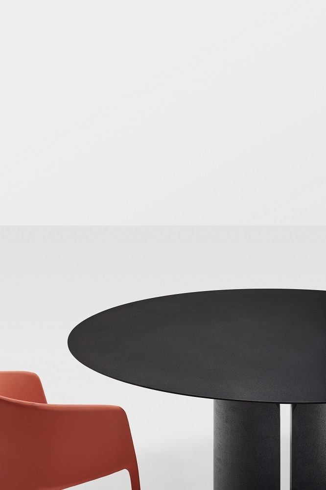 Schwarzer NVL Table von MDF Italia mit rundem Tischblatt und orangefarbenem Stuhl.