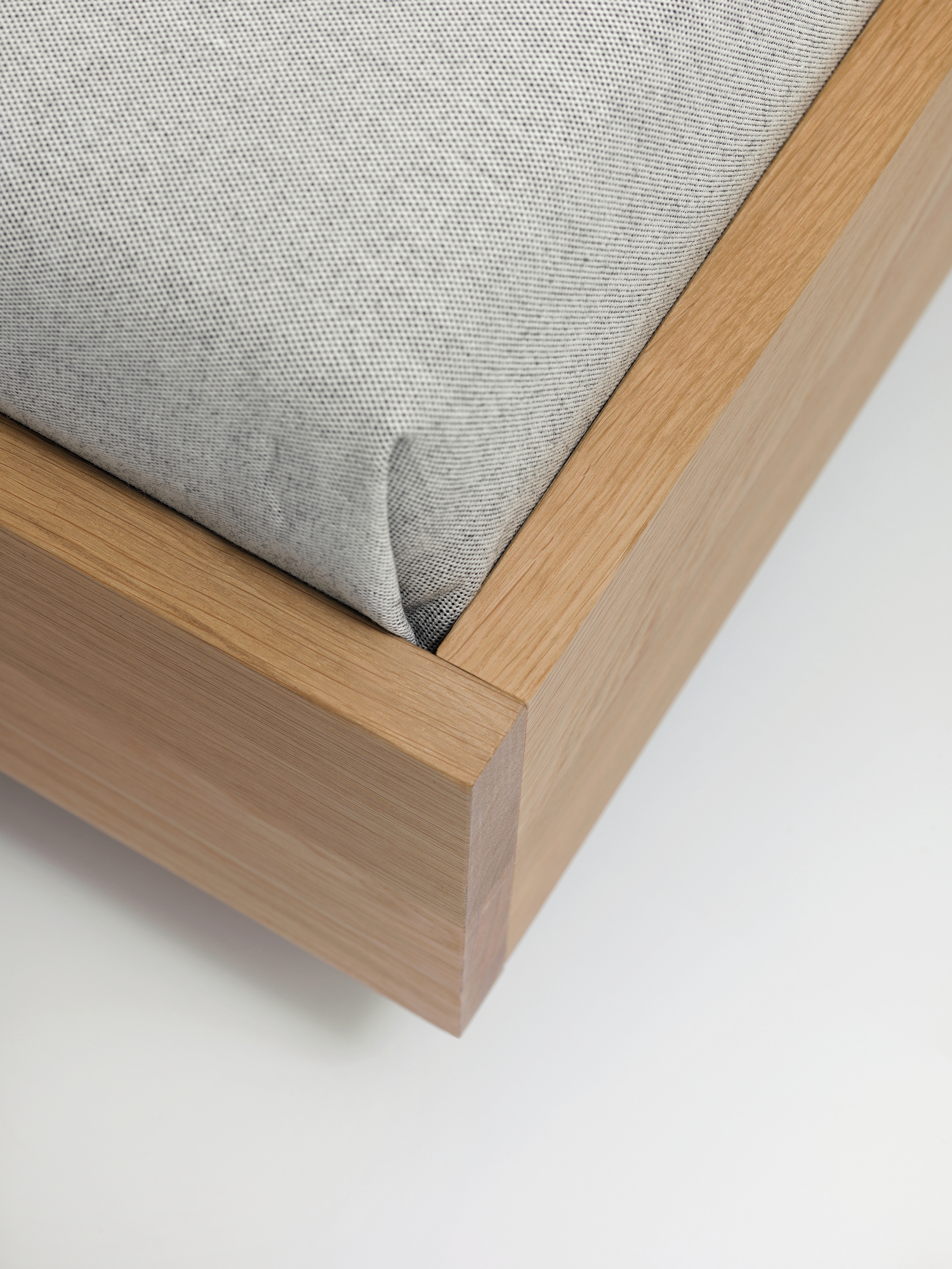 Detailaufnahme vom Simple HI Holzbett mit hellem Holzrahmen und grauem Stoffbezug.