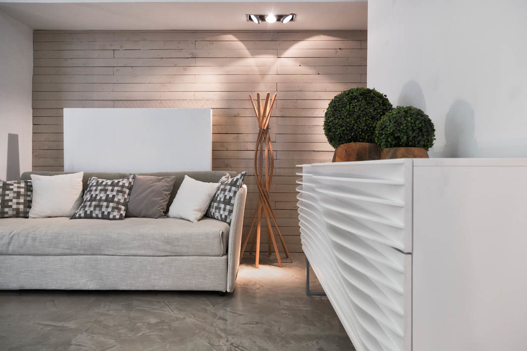 Casamania Horm Twist Garderobenständer aus Buchenholz neben modernem Sofa und weißem Sideboard im Wohnzimmer.