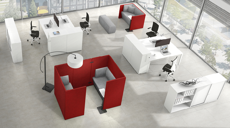 Helle Bürolandschaft mit weißen Schreibtischen, Bürostühlen und roten Assmann Syneo Bench Sitzinseln für Besprechungen.