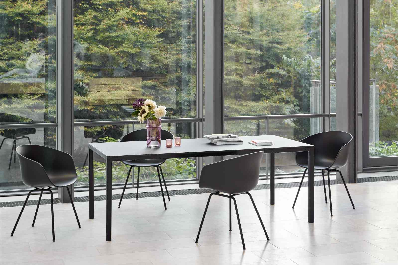 Esstisch mit vier schwarzen About A Chair AAC26 Stühlen von Hay vor Fensterfront.
