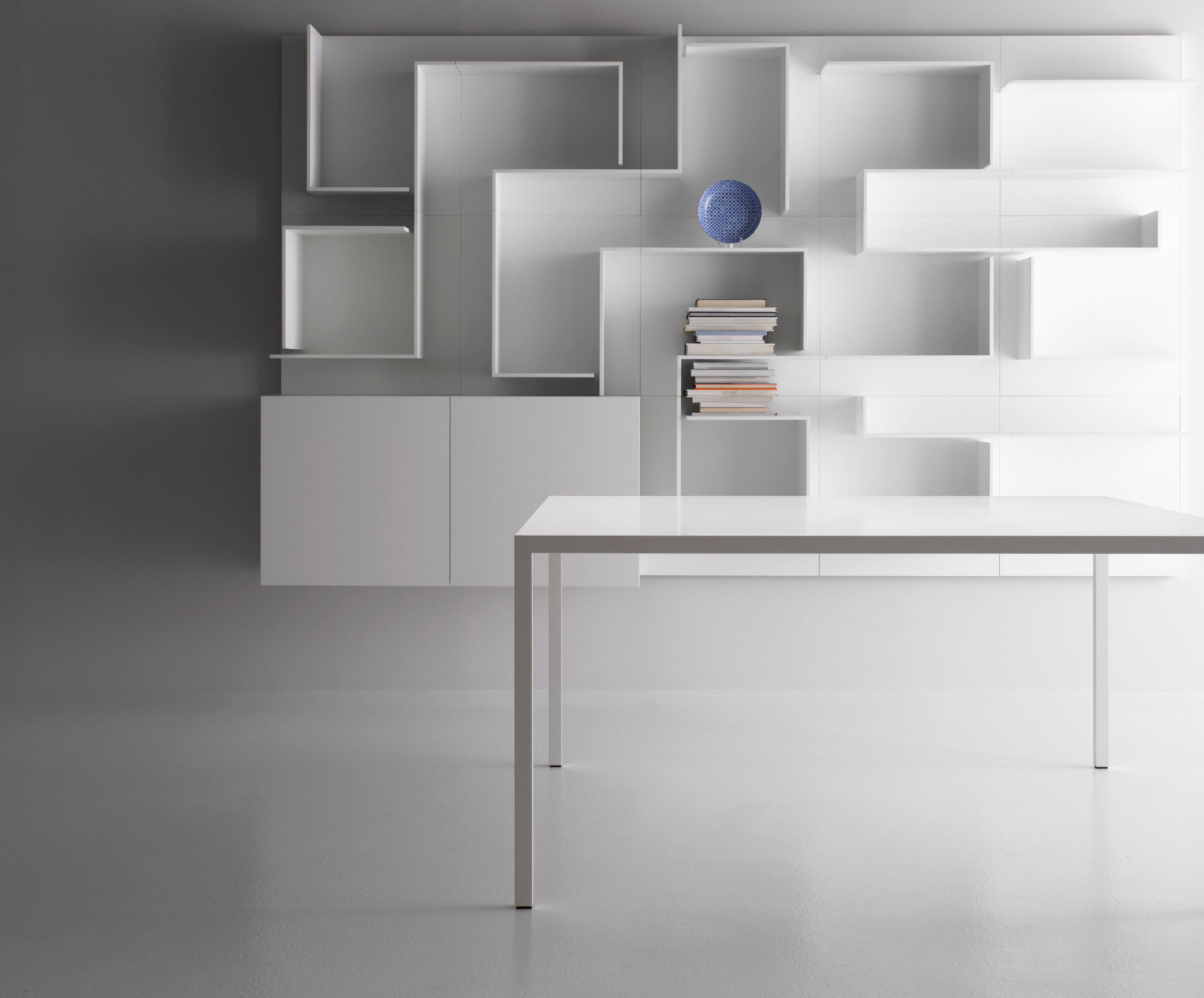 Weißer Tense Tisch von MDF Italia mit passendem weißen Wandregal und Bücher im Hintergrund.