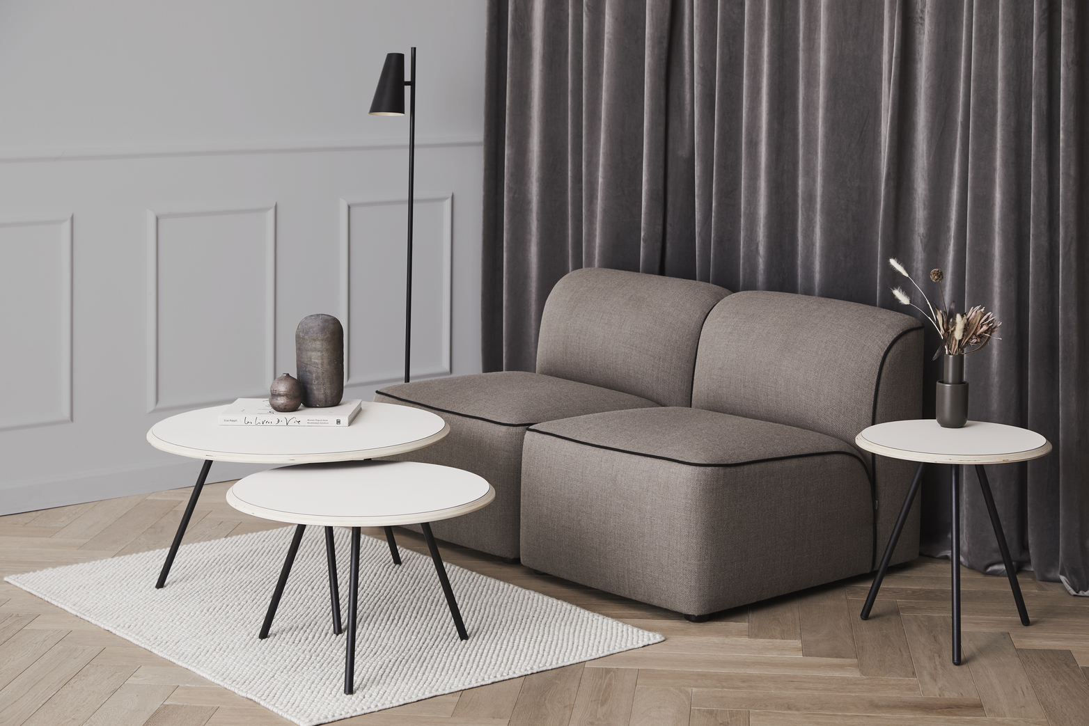 Beiger Soround Couchtisch von Woud mit schwarzem Gestell und passendem Sofa im modernen Wohnzimmer.