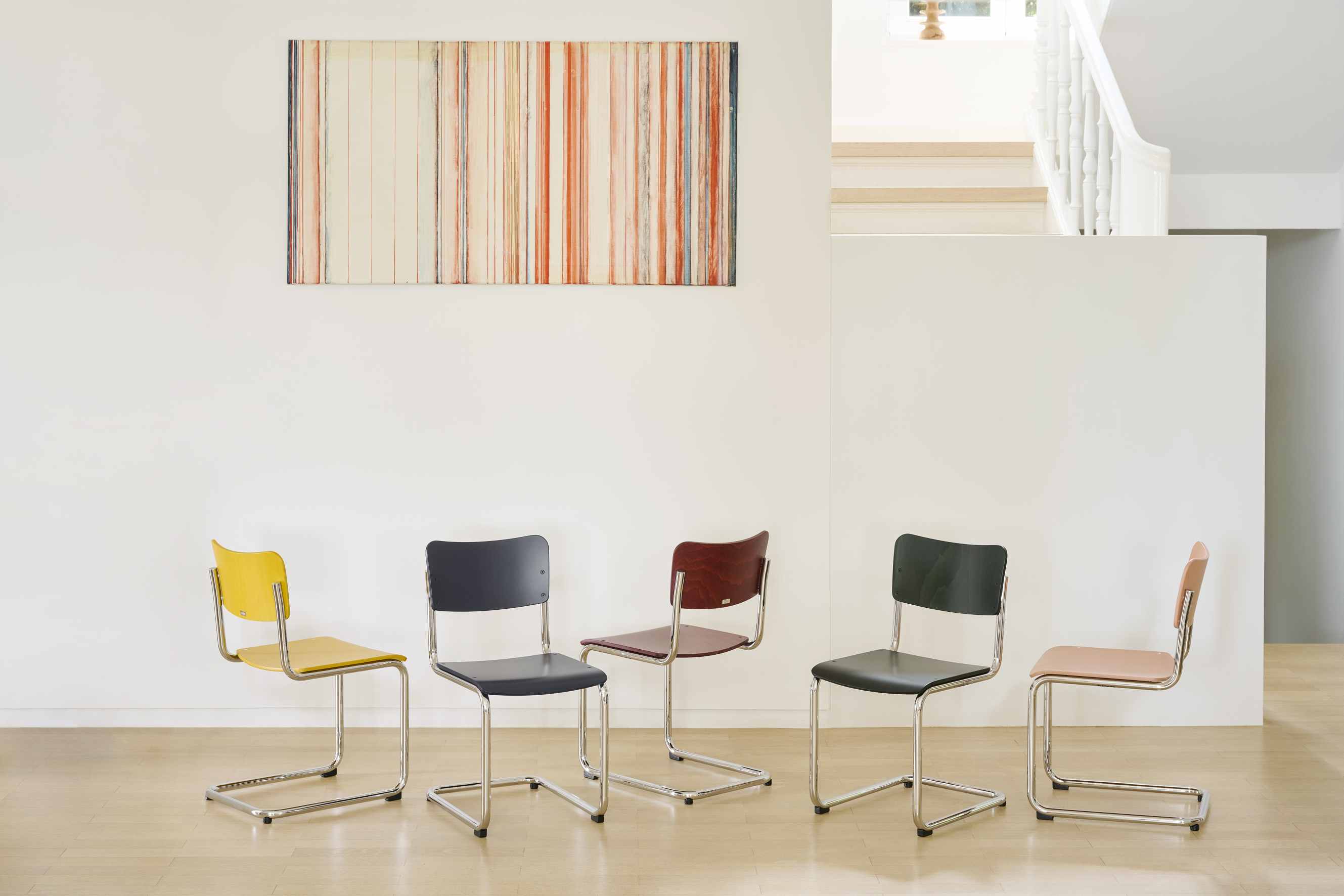 Fünf S 43 K Thonet Kinderstühle Freischwinger in verschiedenen Farben mit Stahlrohrgestell vor weißer Wand.