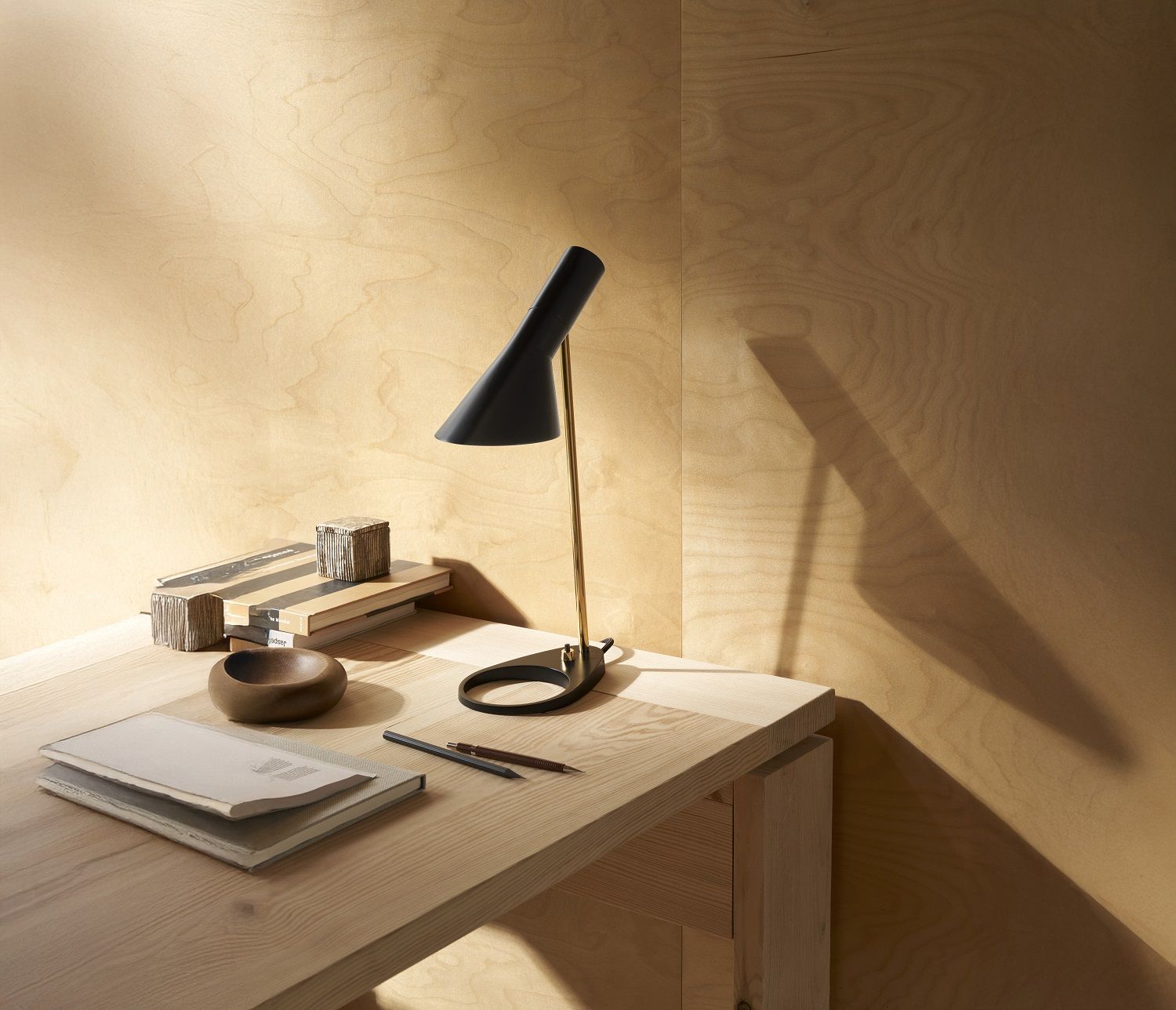 AJ Mini Tischleuchte von Louis Poulsen in Schwarz auf einem Schreibtisch mit Büromaterial.