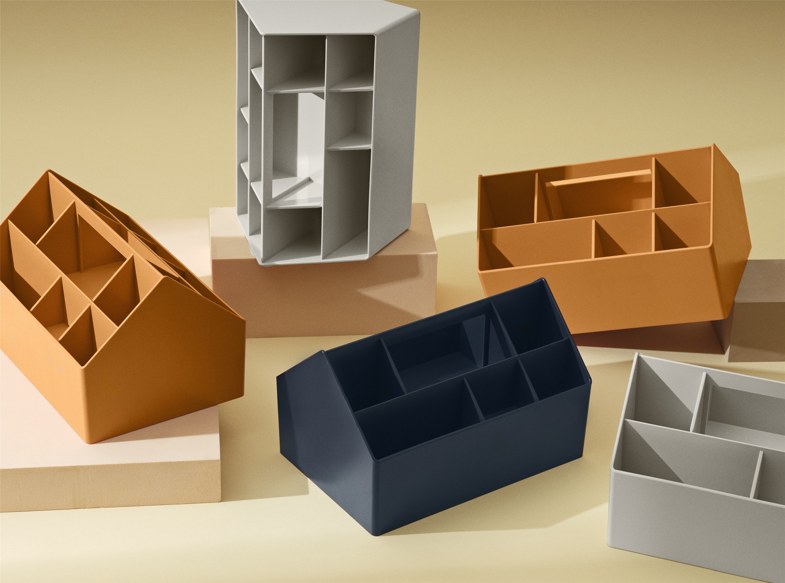 Verschiedenfarbige Muuto Sketch Toolbox Organisationsboxen für Bürobedarf und Schreibtischaccessoires auf beigem Hintergrund.