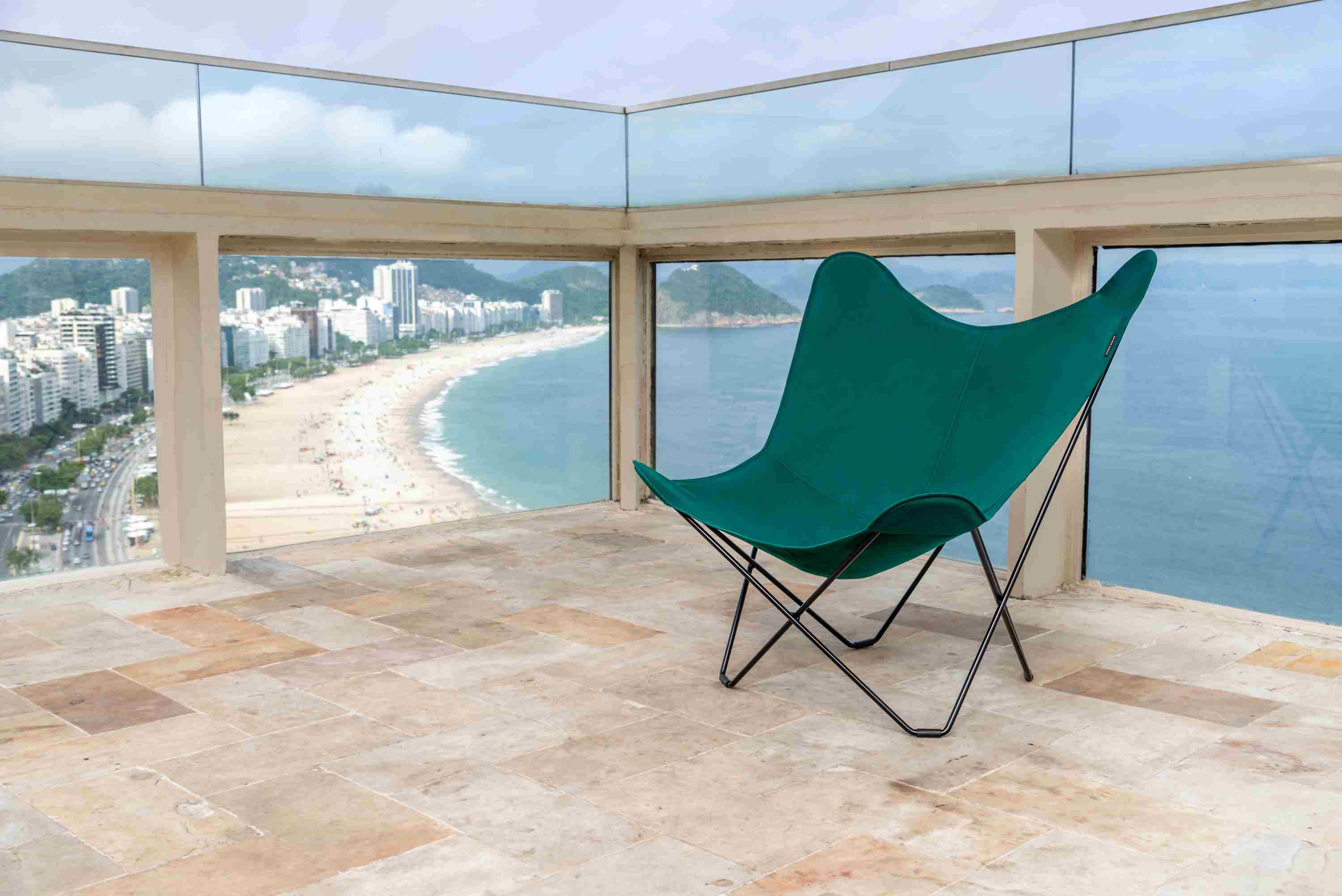 Mariposa Sessel in Waldgrün vor Strandkulisse. Outdoor Butterfly Chair mit schwarzem Gestell.