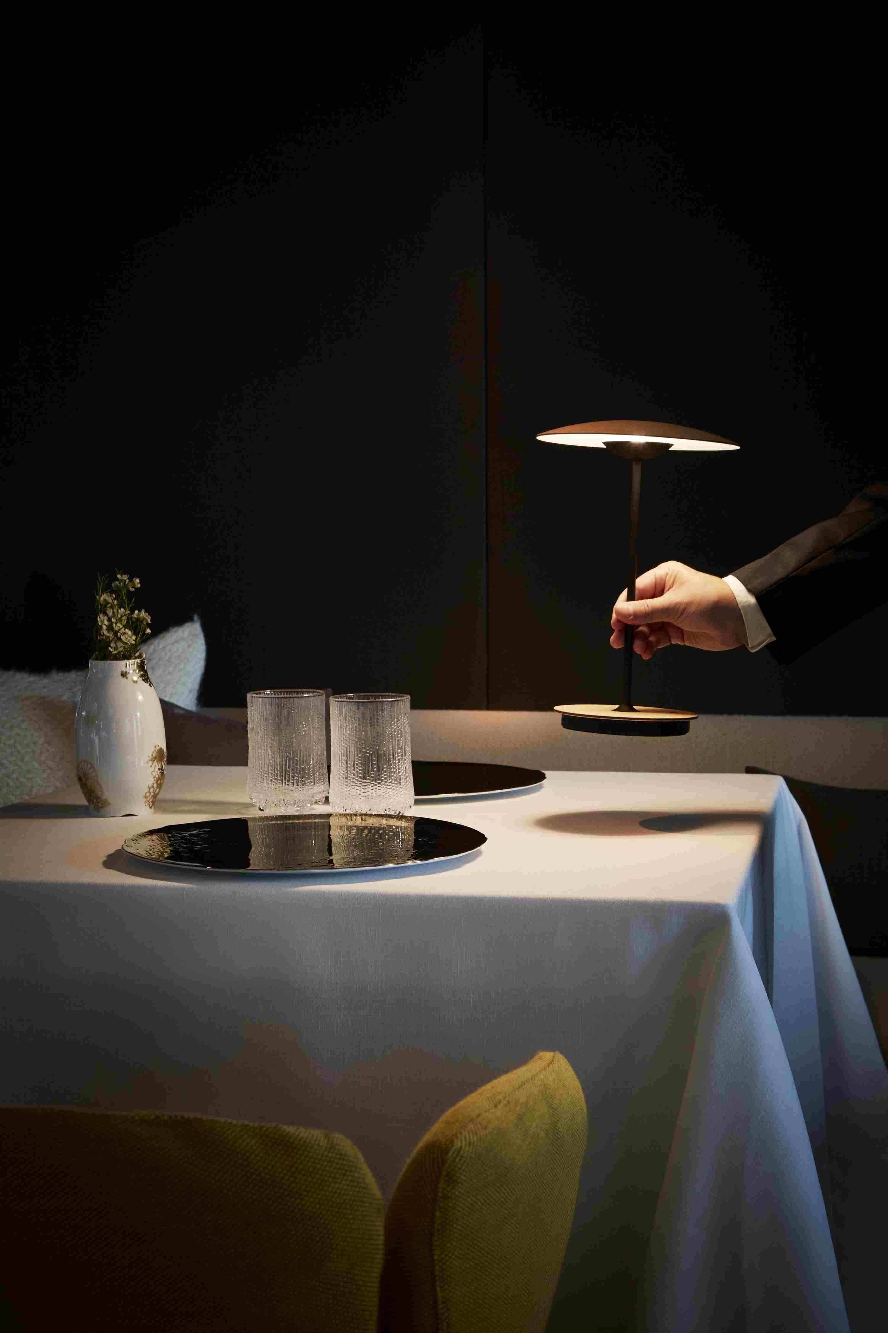 Ginger 20 M LED Akkuleuchte Eiche auf gedecktem Tisch, warmes Licht, elegante Tischleuchte.