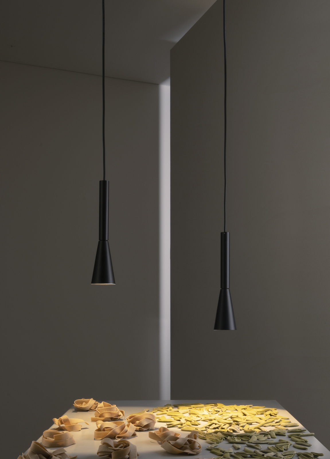 Zwei schwarze Colibrì Pendelleuchten von Martinelli Luce über einem Tisch mit Pasta.