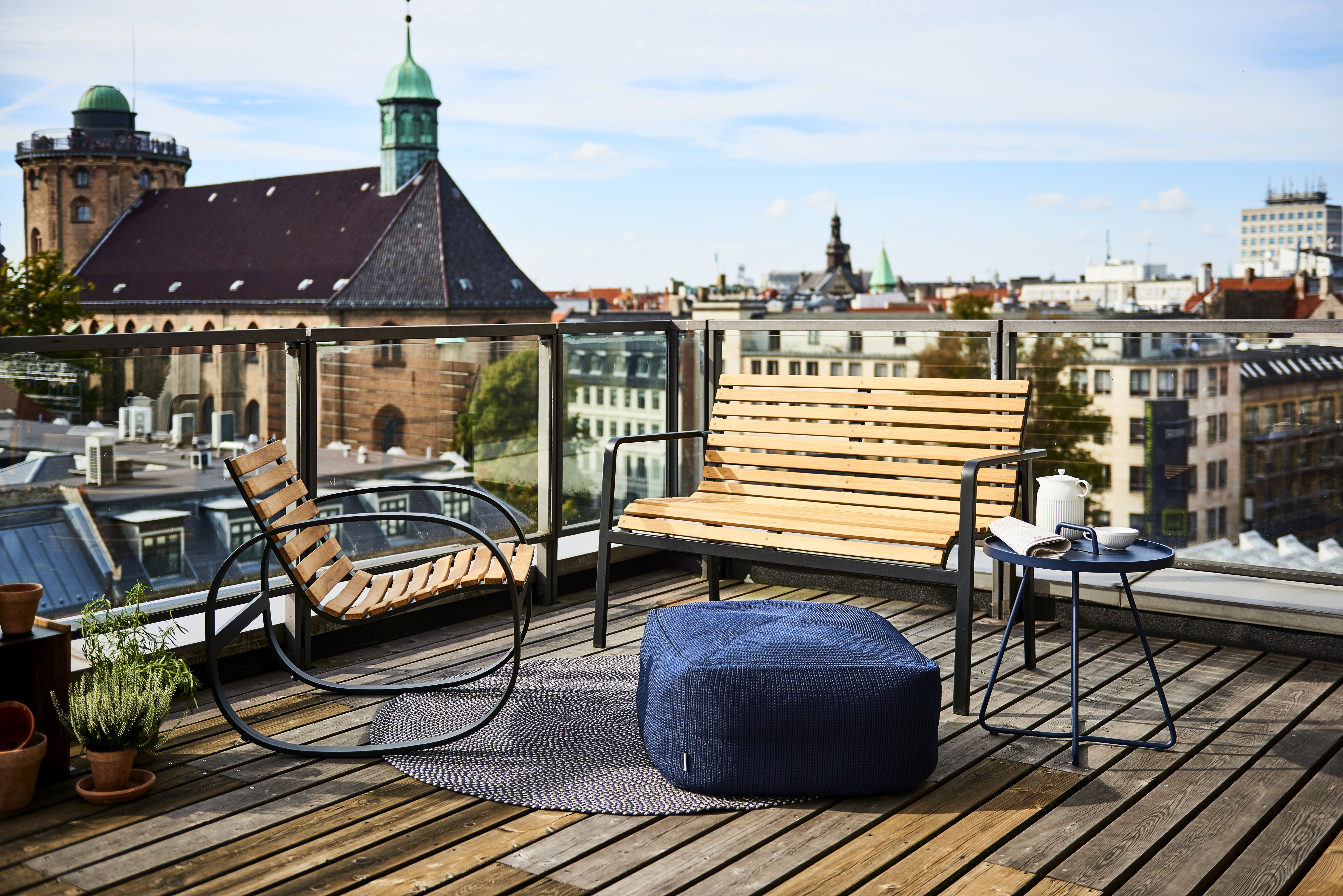 Parc Schaukelstuhl von Cane-Line auf einer Dachterrasse mit Bank, Hocker und Beistelltisch. Outdoor Möbel.